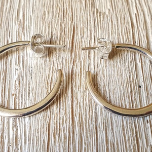May include: A pair of silver hoop earrings with a smooth, rounded finish. The earrings are simple and elegant, and would make a great addition to any jewelry collection.