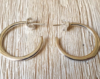 May include: A pair of silver hoop earrings with a smooth, rounded finish. The earrings are simple and elegant, and would make a great addition to any jewelry collection.
