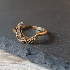 Könnte beinhalten: Goldener Halbmondring mit einem zarten, filigranen Design. Der Ring ist aus Metall und hat ein schlichtes Band.