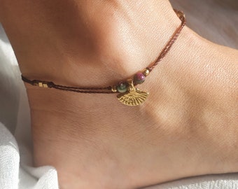 May include: A brown ankle bracelet with a gold charm and green and pink beads.