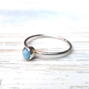 Könnte beinhalten: Ein zarter Silberring mit einem hellblauen Edelstein. Der Ring ist schlicht und elegant, perfekt für den Alltag.
