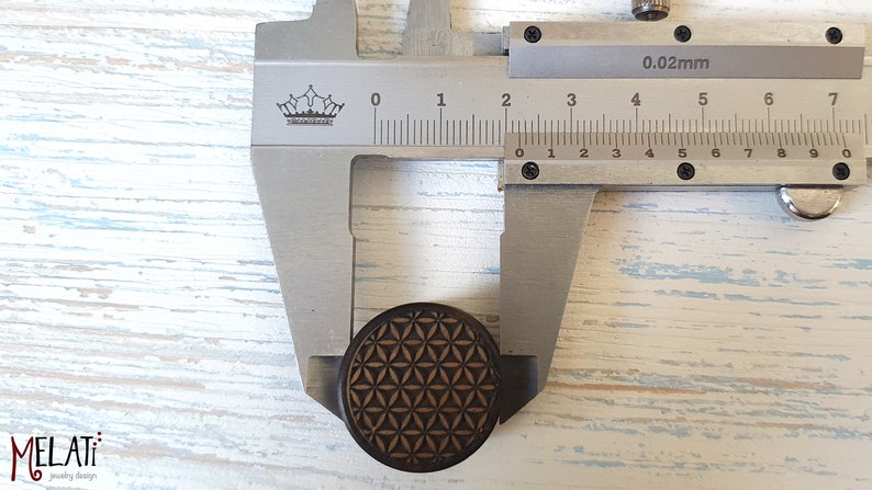 May include: A close-up of a wooden round plug with a geometric pattern, measured with a caliper. The caliper reads 0.02mm and shows a measurement of 2.5 cm.