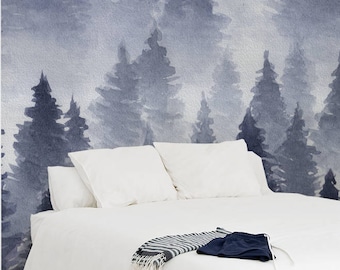 Op de afbeelding: Een wit bed met witte beddengoed en een blauw-wit gestreepte deken. Het hoofdeinde is een aquarelmuurschildering van een blauw bos met mist.