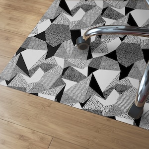 May include: Black and white geometric patterned floor mat with a black and silver office chair on top of it.