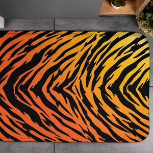 Op de afbeelding: Een badmat met een tijgerstreepdessin in zwart, oranje en geel.