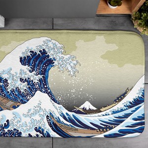 以下が含まれることがあります： 神奈川沖浪裏（かながわおきなみうら）の有名な日本の木版画にインスパイアされた、青と白の波のデザインのバスマットです。