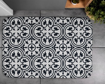 May include: A black and white bath mat with a geometric pattern of interlocking circles and leaves. The pattern is reminiscent of traditional tile designs.