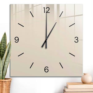 May include: A square wall clock with a smooth beige face, featuring black numerals at the 12, 3, 6, and 9 o'clock positions. The clock has thin black hour and minute hands, with simple black tick marks representing the remaining hours.