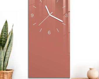 May include: A rectangular wall clock with a smooth, dusty rose-coloured face. The clock features white minimalist hour markers, white numerals at the 12, 3, 6, and 9 positions, and thin white hour, minute, and second hands centred on the surface.