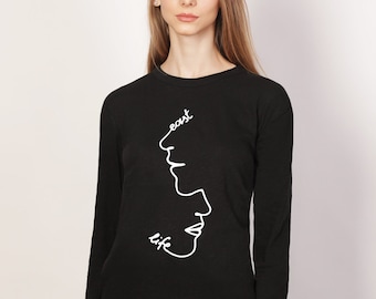 Könnte beinhalten: Schwarzes Langarmshirt mit einer weißen Linienzeichnung von zwei Gesichtern und den Worten "east life" auf der Vorderseite.