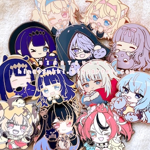 Puede incluir: Una colección de diez pines de esmalte con personajes de estilo anime con varios colores de cabello y atuendos, incluyendo diseños en morado, azul, rosa y rubio. El texto "hinatsukki.bigcartel.com" está impreso en el centro de los pines.