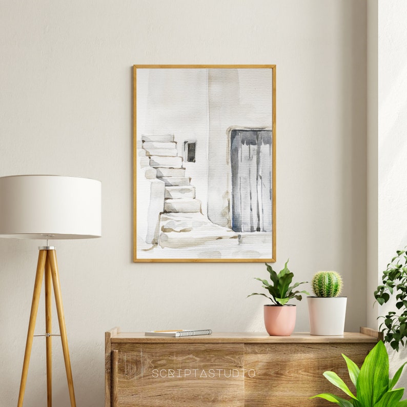 May include: A watercolor painting of a white building with a blue door and a set of stairs leading up to it. The painting is framed in a light wood frame.