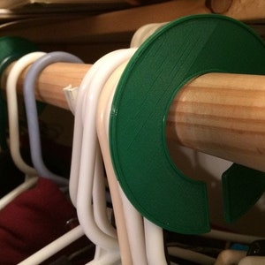 Puede incluir: Organizadores de perchas de plástico verde para una barra de armario. Los organizadores están diseñados para evitar que las perchas se deslicen de la barra.