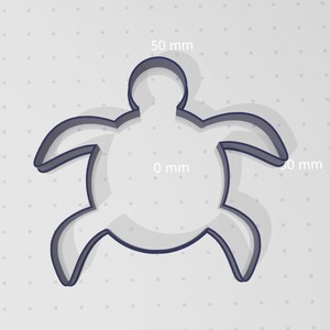 May include: A cookie cutter in the shape of a turtle, measuring 50 mm wide and 50 mm long. The cutter is made of metal and has a smooth, shiny finish.