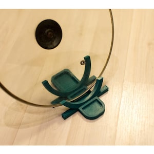 Puede incluir: Soporte para tapas de plástico turquesa con dos soportes curvos para mantener una tapa de vidrio en posición vertical.