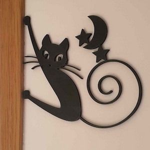 以下が含まれることがあります： 猫のシルエットと三日月と星が描かれた黒い金属製の壁飾り