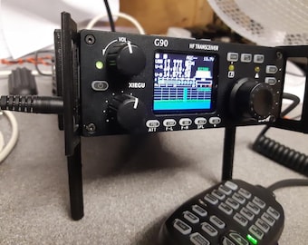 May include: Black G90 HF transceiver with a display showing a blue and green spectrum. The device has multiple knobs and buttons, including a volume control and power button. A microphone with a keypad is in the foreground.