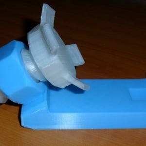 May include: A 3D printed phone stand with a blue base and a white, adjustable phone holder. The holder is shaped like a nut and bolt.