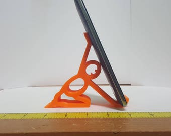 Peut inclure: Support de téléphone imprimé en 3D de couleur orange en forme de personne tenant un téléphone. Le téléphone n'est pas inclus.