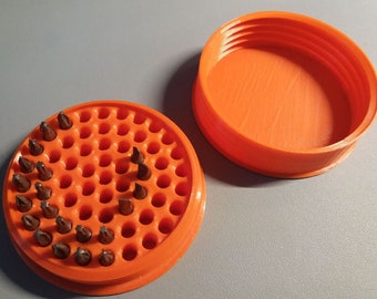 May include: Orange plastic container with a lid, containing a variety of small screwdriver bits. The container has a circular design with multiple holes to hold the bits.