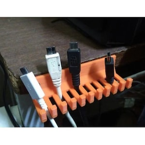 May include: An orange plastic cable organizer with multiple slots to hold cords and wires.  Four cables are shown in the organizer, including a white USB cable, a black USB cable, and two black micro USB cables.