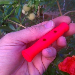 May include: A bright pink plastic handle with two holes. The handle is being held in a hand.