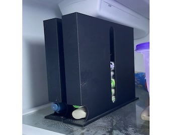 May include: A black plastic organizer with three compartments for storing items. The organizer has a slot for holding items vertically. The organizer is sitting on a white surface.