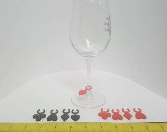May include: Six wine glass charms, three red and three black, with a heart and spade design. The charms are hanging from a clear wine glass.