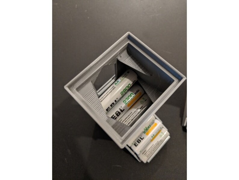 May include: A gray 3D printed battery holder with a stack of AA batteries inside. The batteries are labeled "EBL 2300 mAh".