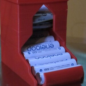 May include: Red plastic battery storage container with a slot for holding AA batteries. The container is filled with Energizer AA batteries.