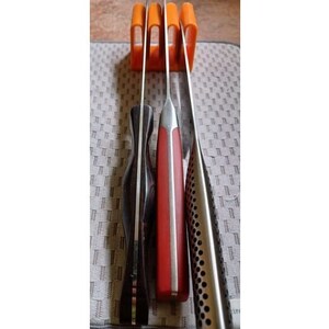 May include: Four knives are stored in an orange plastic knife holder. The knives have black, red, and silver handles.