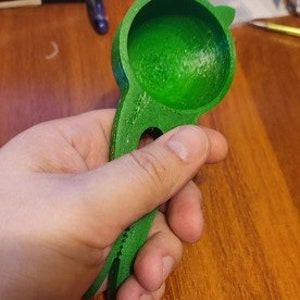 Peut inclure: Une louche en plastique verte en forme de chat avec une poignée. La louche a un intérieur rond et creux.