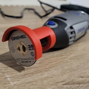 Peut inclure: Gros plan sur un outil rotatif Dremel avec un disque de coupe rouge. Le disque est marqué "38 mm EZ SpeedClic This Side Up".