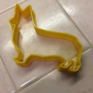 May include: A yellow plastic cookie cutter shaped like a corgi dog.
