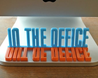 Könnte beinhalten: Ein 3D-gedrucktes Schild mit der Aufschrift "In the office, out of office" in blauen und orangen Buchstaben.