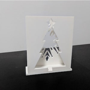 May include: White cardboard cutout of a Christmas tree with a star on top. The tree is designed to be a light holder.