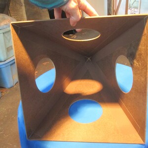 May include: A brown wooden box with four circular openings. The box is open and the inside is visible. The box is sitting on a blue surface.