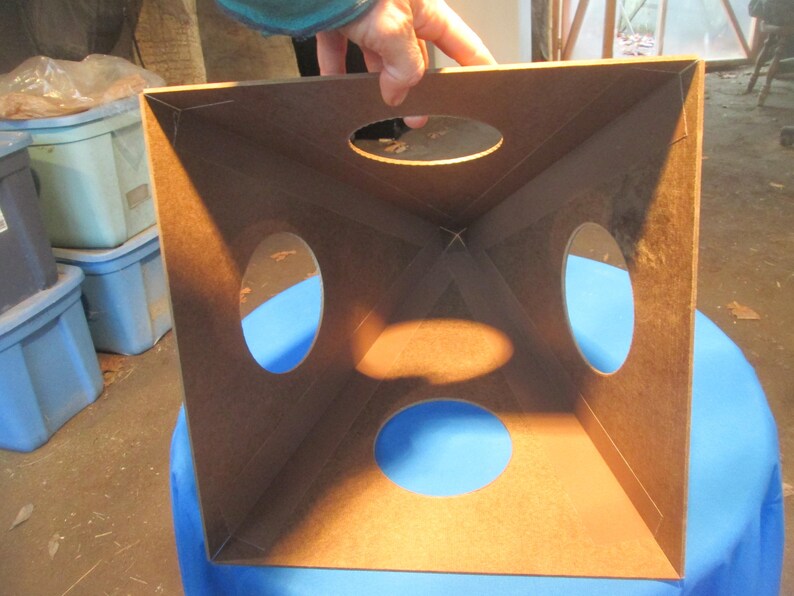 May include: A brown wooden box with four circular openings. The box is open and the inside is visible. The box is sitting on a blue surface.