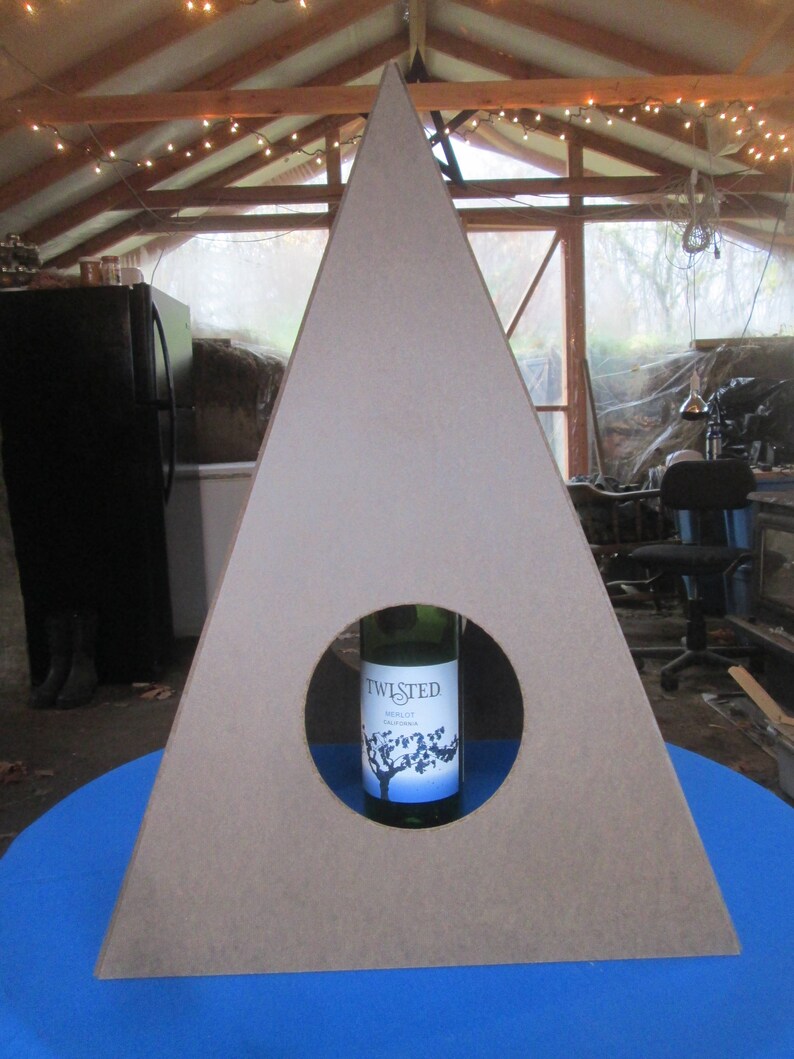 May include: A triangular wooden stand with a circular cutout in the center. A bottle of Twisted Merlot wine is placed in the cutout.