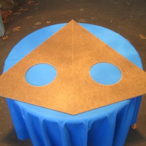 May include: A triangular piece of wood with two circular cutouts. The wood is a light brown color and the cutouts are painted blue.