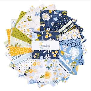 May include: A stack of square fabric swatches arranged in a fan shape, featuring various patterns including daisies, honeycombs, stripes, and butterflies in navy blue, yellow, white, and green. A white paper band reads Sunshine & Dandelions.