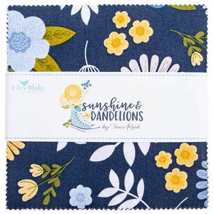 Op de afbeelding: Een stapel vierkante stofstalen met een donkerblauwe achtergrond en een bloemenpatroon van lichtblauwe en gele bloemen, witte bladeren en groene stengels. Een witte papieren band omwikkelt het midden met de tekst Sunshine & Dandelions.