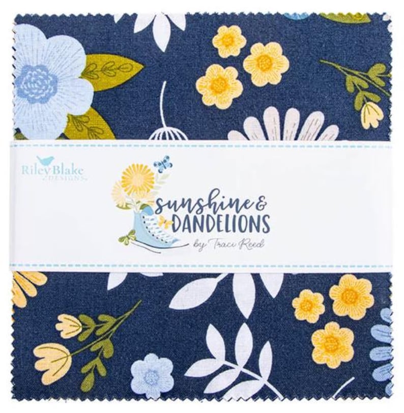 Op de afbeelding: Een stapel vierkante stofstalen met een donkerblauwe achtergrond en een bloemenpatroon van lichtblauwe en gele bloemen, witte bladeren en groene stengels. Een witte papieren band omwikkelt het midden met de tekst Sunshine & Dandelions.