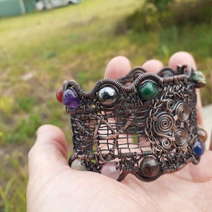 May include: A copper wire wrapped bracelet with a Celtic knot design and various gemstones including amethyst, malachite, and hematite.