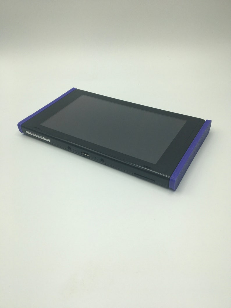 May include: A black Nintendo Switch console with purple edges. The console is in a closed position, with the screen facing up.