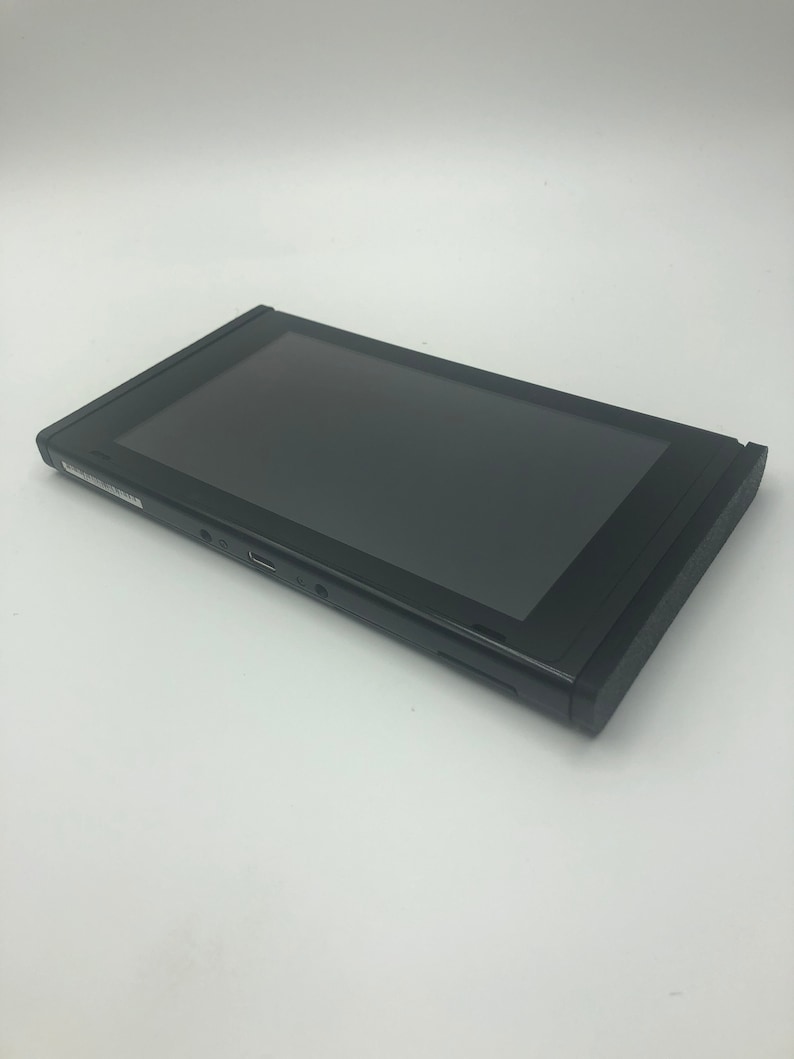 May include: A black Nintendo Switch console with a black screen. The console is closed and lying on its side.