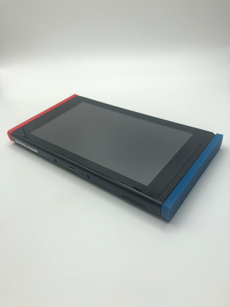 May include: A black Nintendo Switch console with red and blue joy-con controllers. The console is in a closed position.