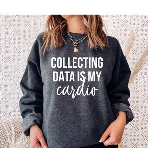 May include: A dark gray sweatshirt with the text "COLLECTING DATA IS MY cardio" printed in white.