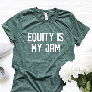 以下が含まれることがあります： 前面に白い文字で「Equity is my jam」とプリントされた緑色のTシャツです。