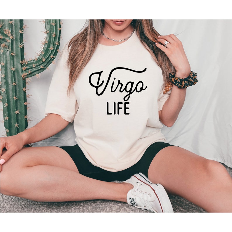 May include: A white t-shirt with black text that reads "Virgo LIFE" in a cursive font.
